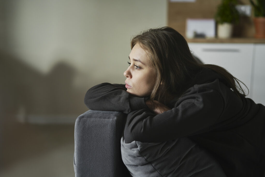 woman sitting on sofa looking sad